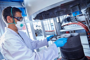 Scientist removing 3D printed carbide parts from a sintering oven